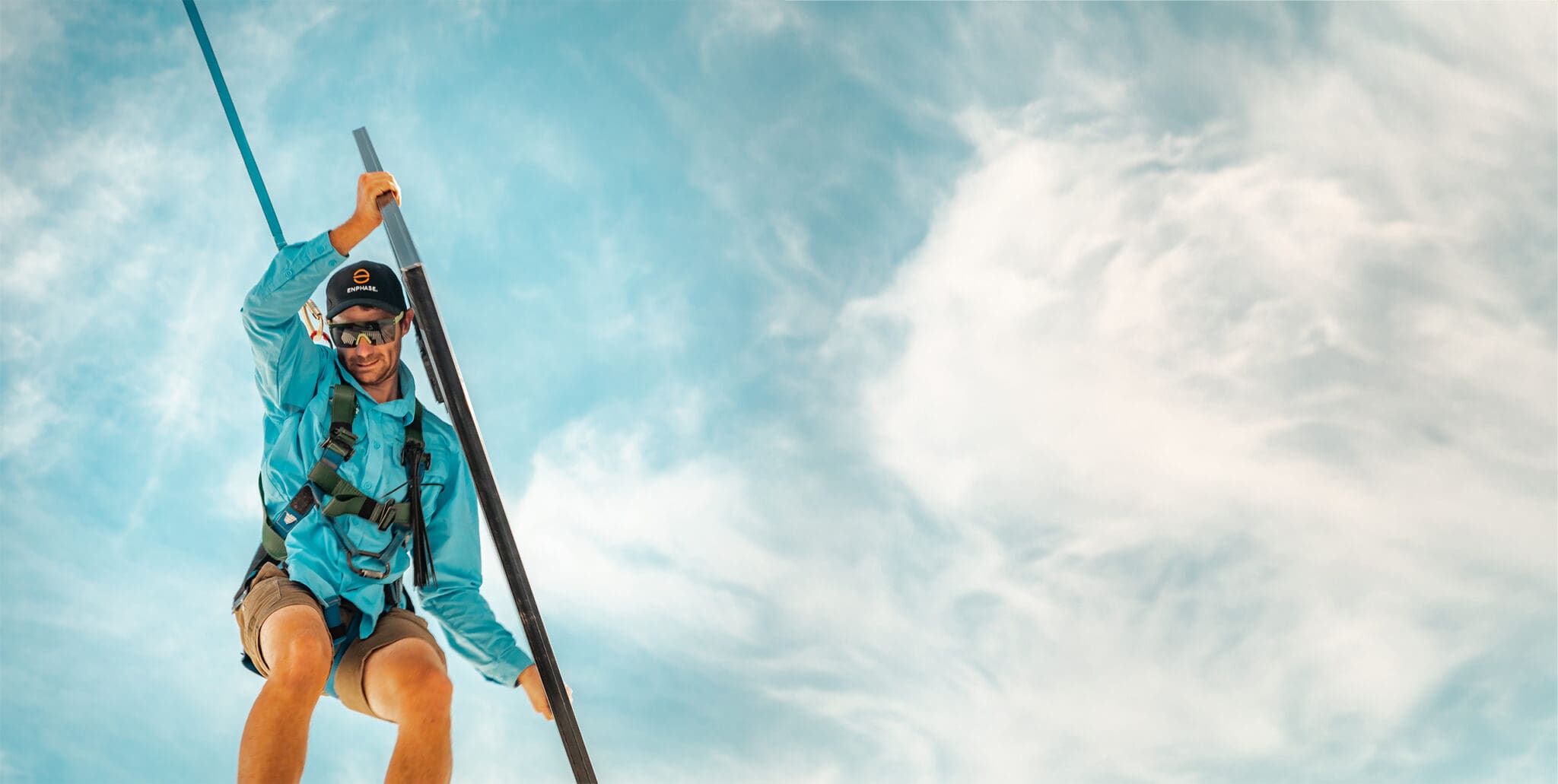 A man in a blue shirt is holding a pole in the air.