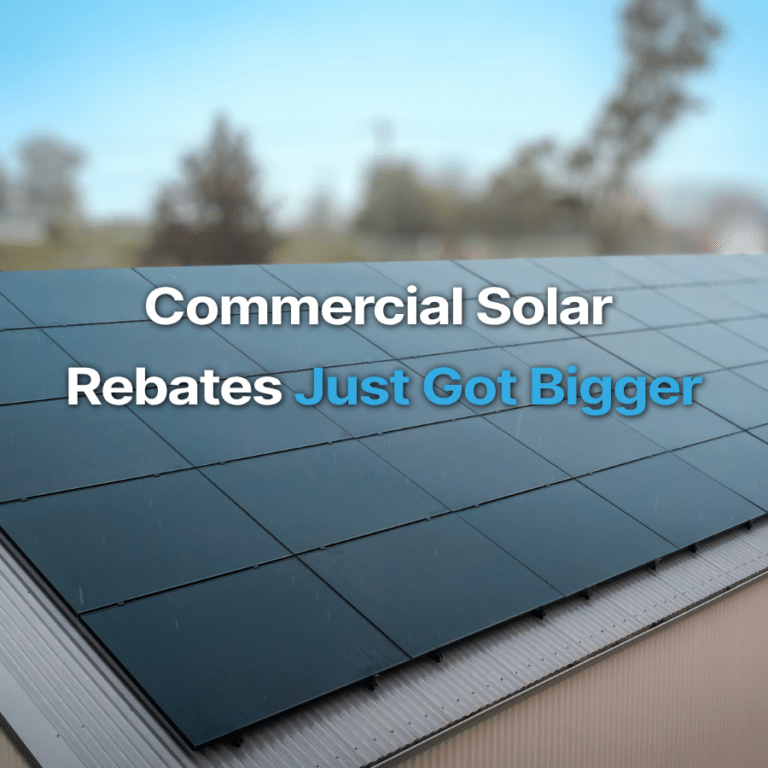 Close-up of solar panels on a rooftop with the text “Commercial Solar Rebates Just Got Bigger” overlaid on a blurred outdoor background.