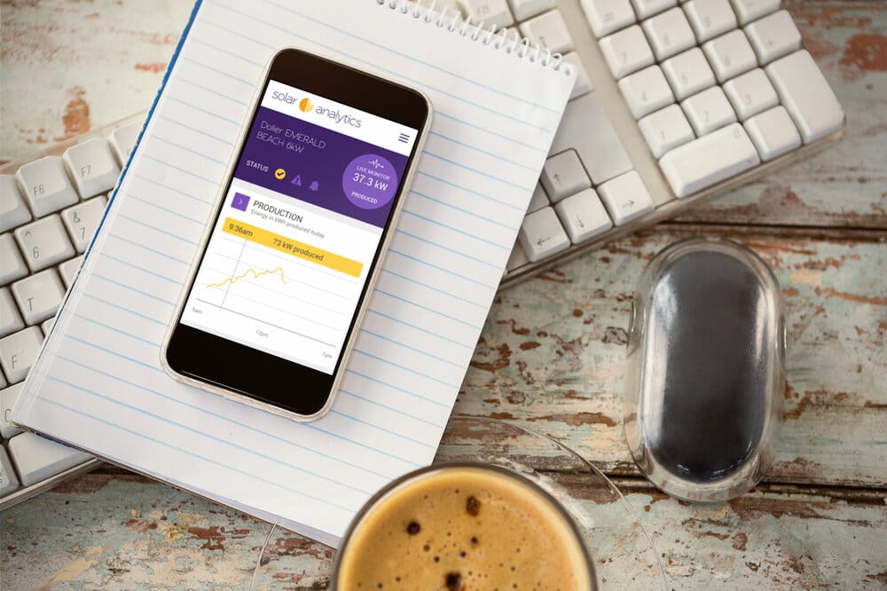 A smartphone on a desk next to a cup of coffee and a keyboard.