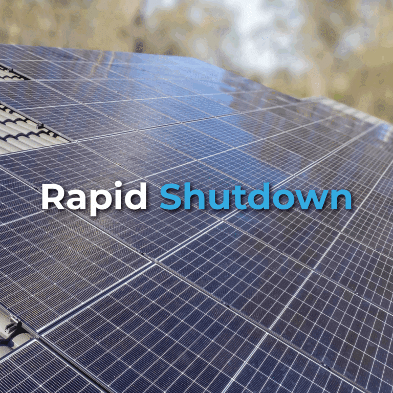 Close-up of solar panels on a roof with the words "Rapid Shutdown" overlaid in white and blue text. Trees are blurred in the background.